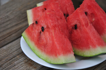 pieces of juicy watermelon on a white plate close-up. selective focus. plate with sliced ​​watermelon on a wooden table