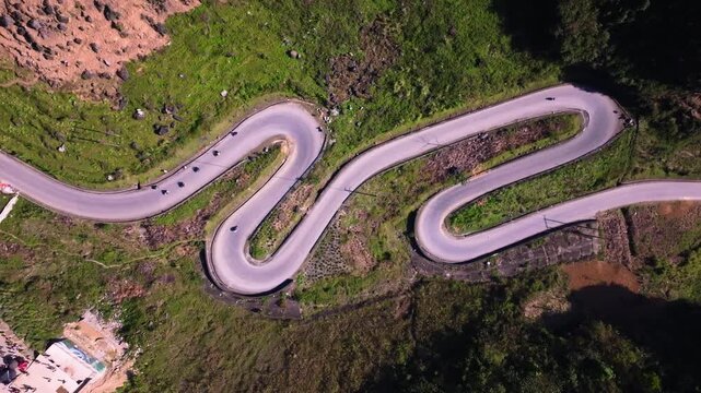 This aerial footage captures the winding roads of Ha Giang in Vietnam, as motorcycles navigate the and challenging terrain. The shot highlights the curves of the road and the beauty of the landscape.