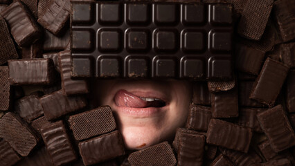 The face of a caucasian woman surrounded by chocolates. girl showing tongue. 