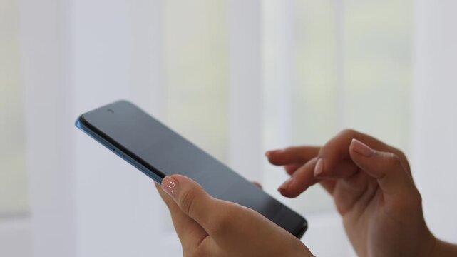 The girl holds the phone in her hands. A woman scrolls with her fingers on a touchscreen smartphone.