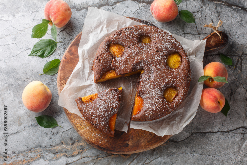 Wall mural fruit chocolate peach sponge cake summer dessert close-up on wooden board on table. horizontal top v