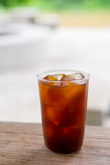 Iced americano coffee in glass on a wooden table in a cafe.