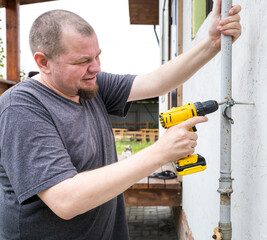 A man is using a drill to fix a pipe