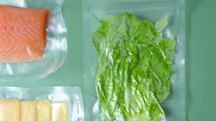 Different types of food packed in vacuum bags on green background top view.