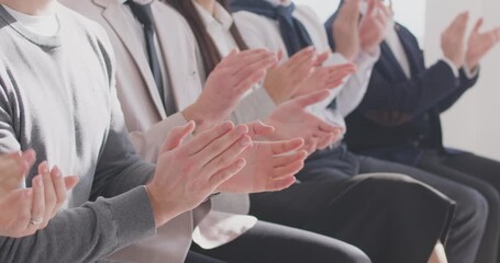 Audience clapping their hands at an educational public event or professional business conference. Camera slowly moves along a row of applauding people in smart formal wear
