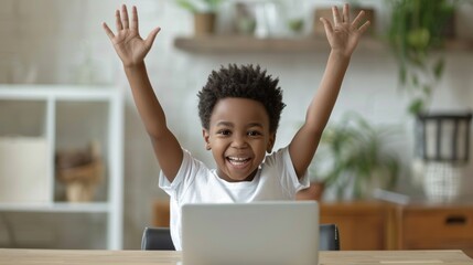 A young boy is sitting at a table with a laptop in front of him, smiling and waving. Concept of happiness and excitement. Online learning