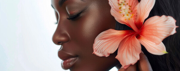 Close-up of a beautiful black woman with a hibiscus flower in her hair on a white background, the concept of skin care and beauty.