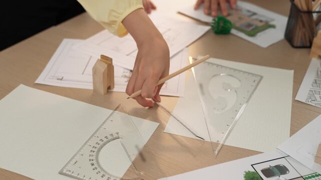 A video of architect use measurement tools and pencil to measure blueprint. Architect design house construction on a table at studio, with architectural plan scattered around. Focus hand. Delineation.