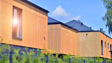 Naklejka premium Residential homes with modern wood facade. Terraced family homes in newly developed housing estate. The real estate market in the suburbs.