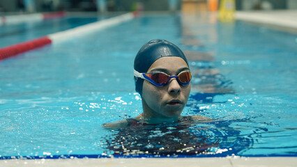 young female paralympic swimmer putting on swimming goggles. Olympic Games.