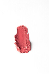 Top view of pink lipstick crushed strokes smudges on white background, abstract cosmetic make up sample