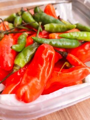 red chilies and green cayenne peppers in plastic containers in the kitchen