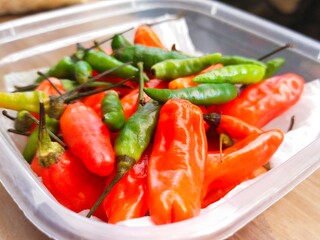 red chilies and green cayenne peppers in plastic containers in the kitchen