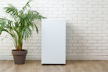 White Refrigerator Against Brick Wall With Palm Plant In Pot