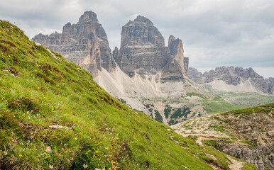 View on the Drie Zinnen ( Tri Crime) mountain peaks during summer. Alpine meadow in the foreground. Cloudy summer day. Beautiful hiking area in the Italian Dolomites. Impressive mountain peaks.