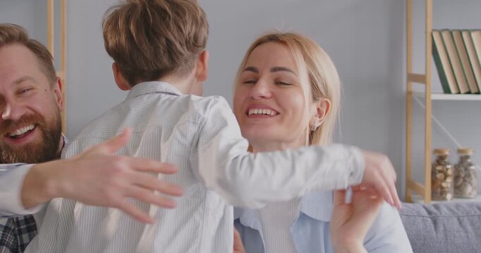 Child runs with joy into arms of his happy parents, who meet him with love and admiration. Mom and dad welcome their little son with open arms, showing boundless love and warmth of family ties.