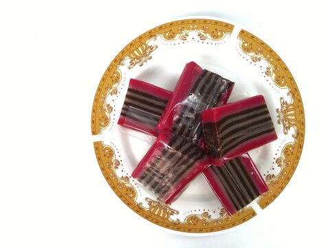 flatlay Lapis beras or kue pepe an Indonesian traditional dessert and street food served on a plate. It is a steamed pandan layered soft rice flour pudding. isolated on white background