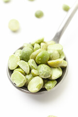 Dry, green peas in iron spoon on white background. Close-up