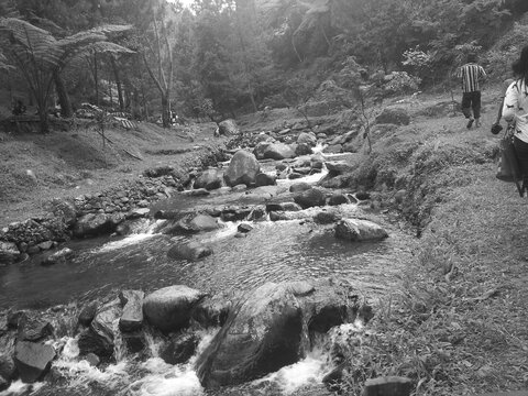 a calm rocky lake in a tourist spot, curug capolaga, indonesia in black and white