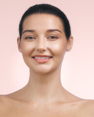 Smiling Young Woman with Radiant Skin Against Soft Pink Background