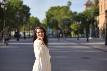 Young woman, natural, with brown hair and white dress, with thumbs up, being a successful woman, smiling and happy. Concept naturalness, simplicity, success, signs, thumbs up.