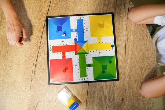 Close-up of hands moving pieces on a Parcheesi board during a game.