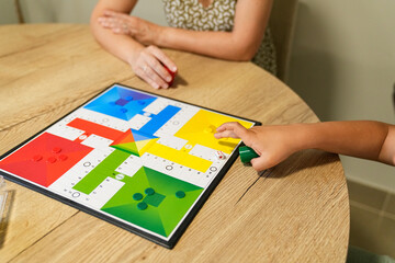 Boy and mother playing Parcheesi, moving pieces on the colorful game board.