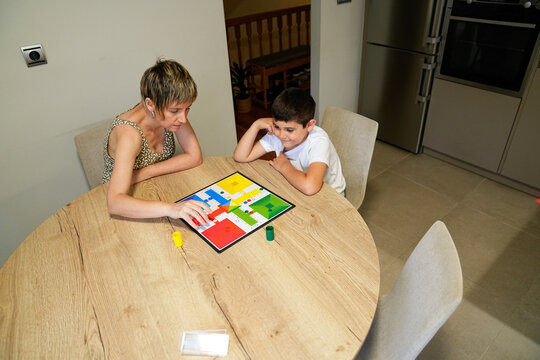 Mother pointing at board game piece while son watches closely