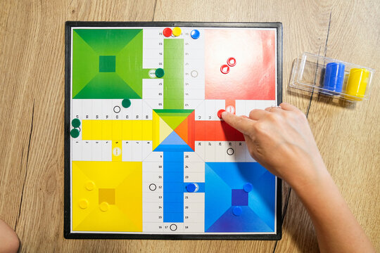 Close-up of board game pieces being moved by mother and son