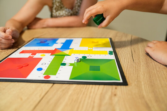 Child making a move in a board game with mother at the table