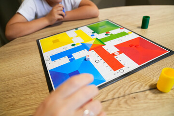 Boy concentrating on a board game while mother moves piece