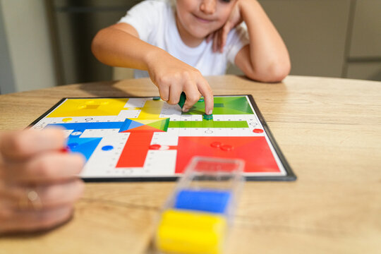 Mother and son enjoying a game of Parcheesi at the dining table.