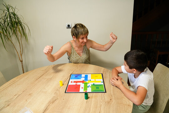 Mother celebrating a win while playing a board game with son