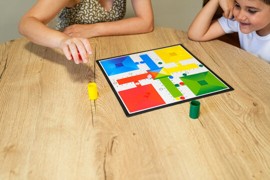 Mother and son engaged in a board game move at the table