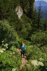 Obraz premium Hiker with backpack and poles on a trail in the mountains