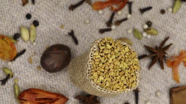 Fenugreek Seeds rotation, close-up. Methi Dana, top view. Scattered spices mix cardamom, Jhaifal, star anise, Javitri, cinnamon, cloves, methi , black and white pepper.  Backgrounds, texture. 4k. 