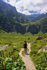 Hiker with backpack and poles on a trail in the mountains