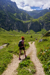 Fototapeta premium Hiker with backpack and poles on a trail in the mountains