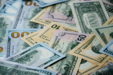 Big amount of US dollar bills in different nominations on table. Many dollar banknotes under natural light