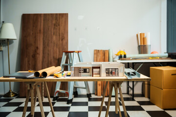 A model of a house showing various rooms such as bedrooms, bathrooms, kitchens, and living rooms, displayed on a desk for an architect's renovation project, highlighting detailed wooden textures.