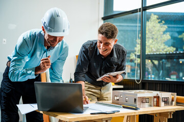 A Caucasian male engineer and an Italian male building contractor are planning and talking at a...