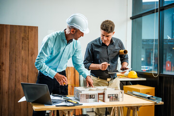 A Caucasian male engineer and an Italian male building contractor are planning and talking at a...