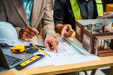 A Caucasian male engineer and an Italian male building contractor are planning and talking at a...