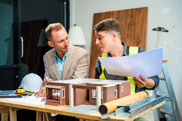 A Caucasian male engineer and an Italian male building contractor are planning and talking at a...