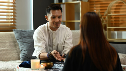 Male tarot reader forecasting predicting future for young woman client. Forecasting and divination concept