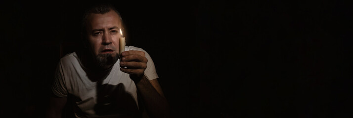 Blackout concept. Frightened man with a candle during blackout.