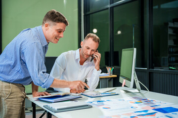 An Italian male and a Caucasian male sit at business desk in office meeting room, discussing...