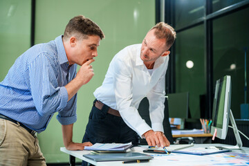 An Italian male and a Caucasian male sit at business desk in office meeting room, discussing...