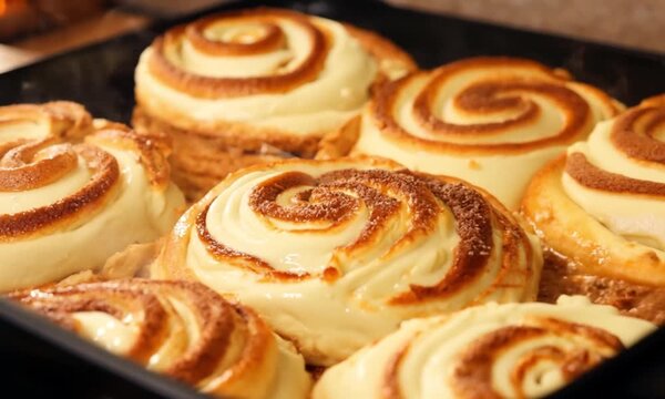 Freshly baked cinnamon rolls with creamy frosting in a baking tray