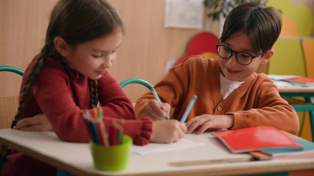 School education studying two funny playing Caucasian little girl daughter child kids children writing in classroom play game drawing fun competition class lesson boy son guy classmates friends write